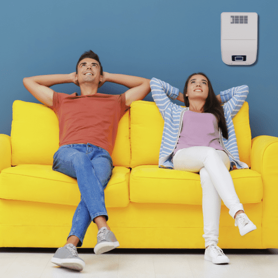un couple est assis dans le canapé avec un système de traitement de l’air fixé au mur 