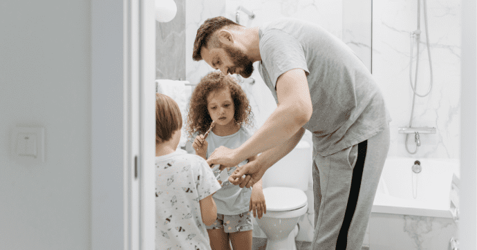 Un papa et ses enfants se brossent les dents dans la salle de bains