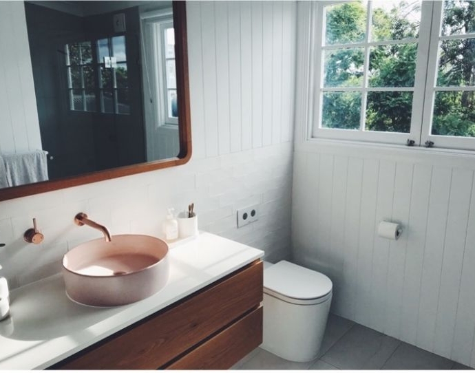 Salle de bains blanche avec lavabo rose et reflets marron foncé 